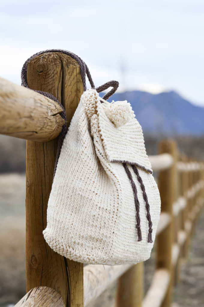 a DIY stitch backpack hanging on a wooden fence