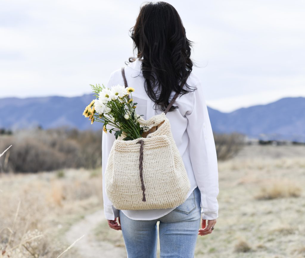 women wearing a homemade knitted bag on her back filled with wildflowers