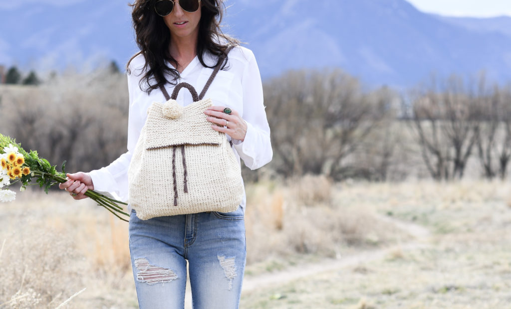 woman wearing off white stitch backpack in a field 