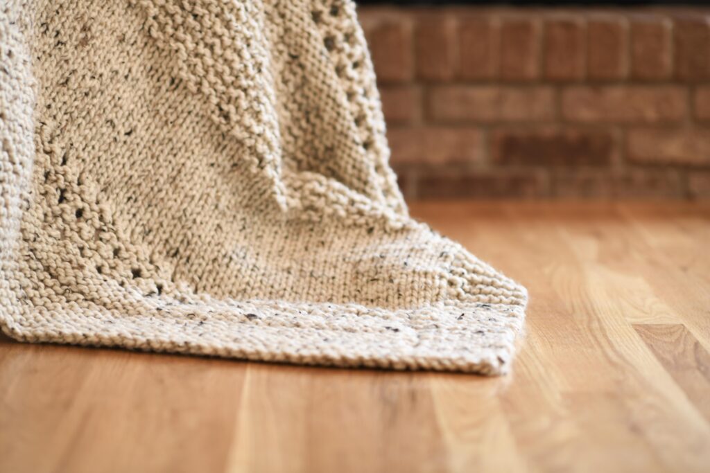 a chunky blanket hanging down onto a wooden floor
